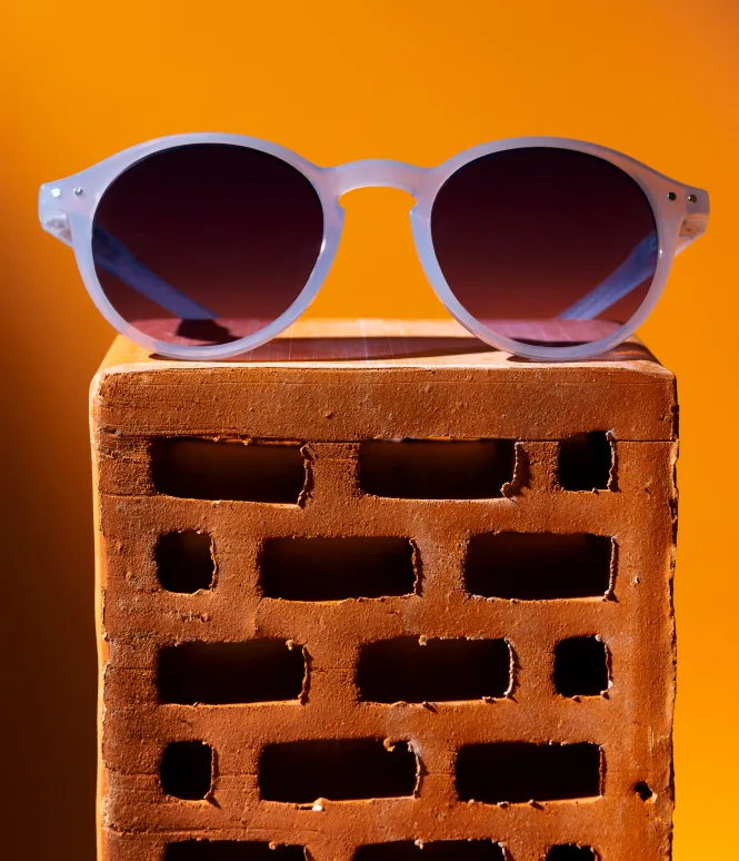 Translucent blue round sunglasses on a studio display